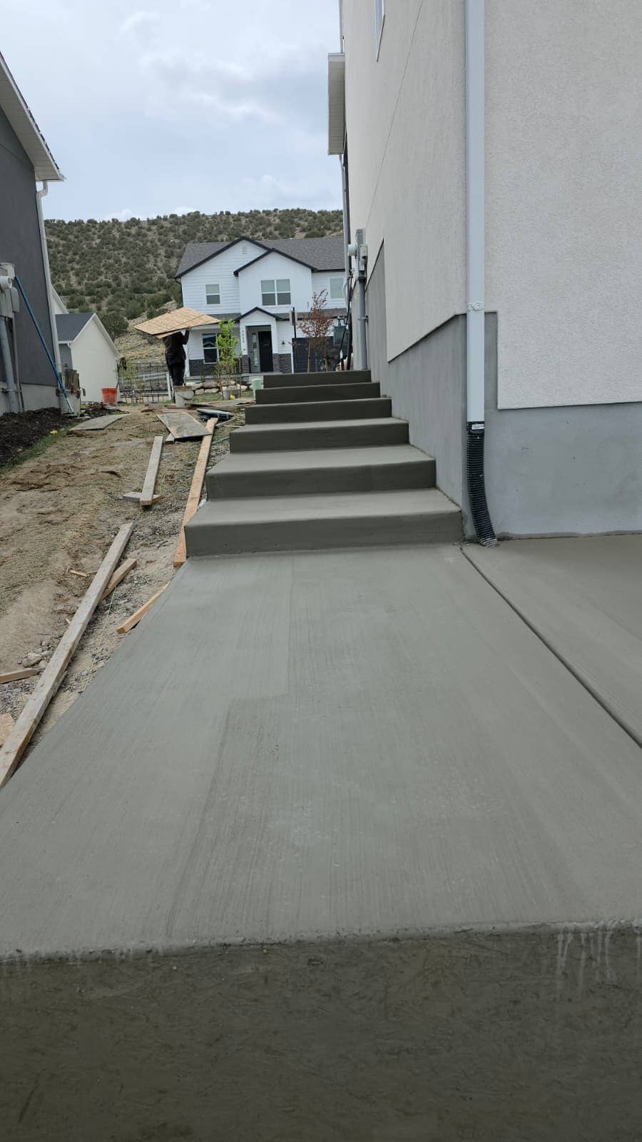 Poured concrete steps running down to a driveway beside a new home