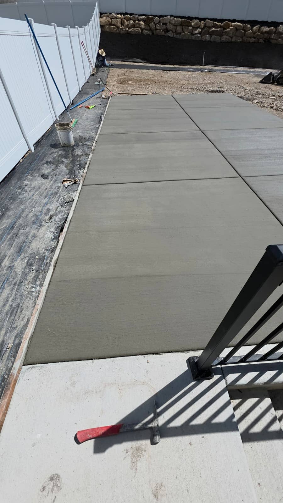 Wide concrete driveway finished up to a railing and the garage apron